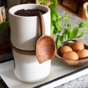 Hand-carved olive wood scoop with hanging handle, approx. 230 mm long, featuring natural grain and warm tone.