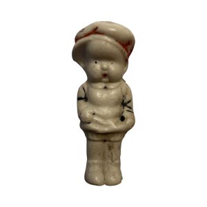 Vintage Japanese bisque boy figurine with red-painted cap and “Japan” mark on the back, showing age-related paint wear.