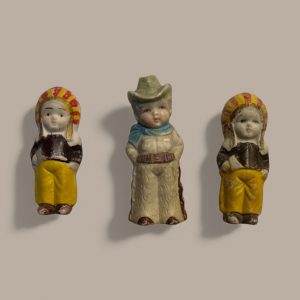 Set of three vintage 1950s Japanese bisque figurines: two children in folk costumes and one cowboy, showing hand-painted details and aged paint wear.