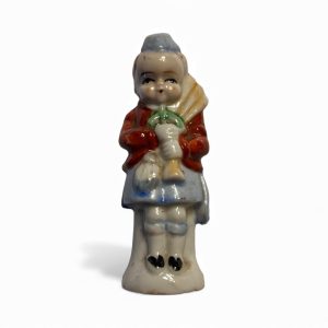 Vintage glazed porcelain figurine of a child in Highland dress holding bagpipes, featuring bright hand-painted colours and a glossy finish.