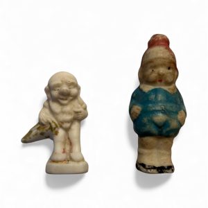 Two vintage 1950s Japanese bisque figures, a grinning gnome and a dwarf in a pointed cap, with aged paint and fairytale styling.