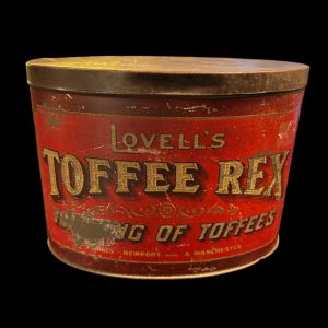 Vintage Lovell’s Toffee Rex tin with “King of Toffees” branding in red and burgundy with gold and black lettering, showing worn patina.