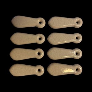 Set of eight vintage ceramic escutcheons with cream crackle glaze, showing aged surface texture and rounded keyhole design.