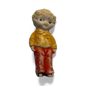 Vintage 1950s Japanese bisque boy figurine with red trousers, yellow jacket, and “Made in Japan” marking on the back.
